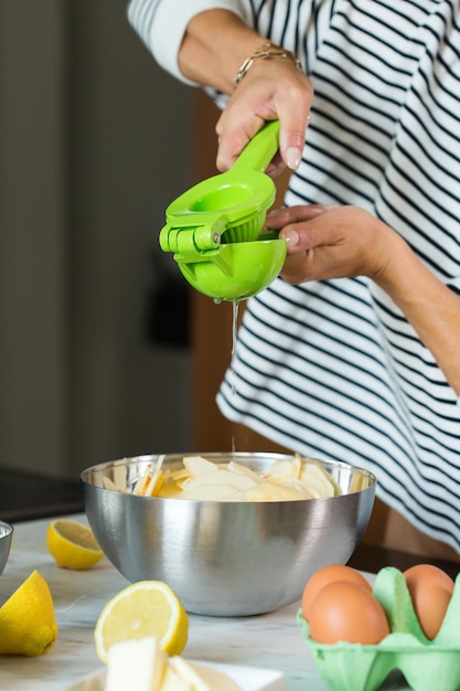 Woman hands squeezing fresh lemon juice while cooking apple pie