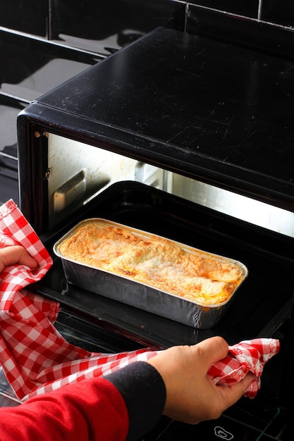 Woman Hands Taking Baking Tray with Lasagna Out of Oven