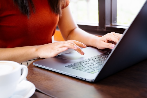 Woman hands typing on laptop keyboard. Woman working at office with coffee