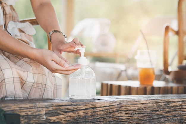 Woman hands using hand alcohol gel or sanitizer bottle dispenser against corona virus Covid19 in cafe Antiseptic hygiene and health concept Prevention of the pandemic virus outbreak