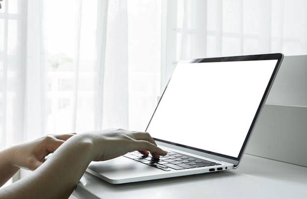 Woman hands using laptop with blank screen on white table at home or office