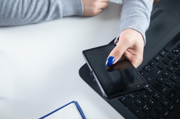 Woman hands with mobile phone and computer keyboard