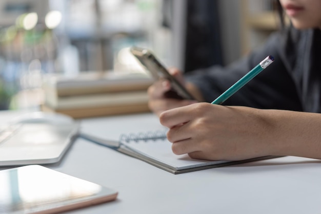 Woman hands with pen writing on notebook in the officelearning education and workwrites goals plans make to do and wish list on desk