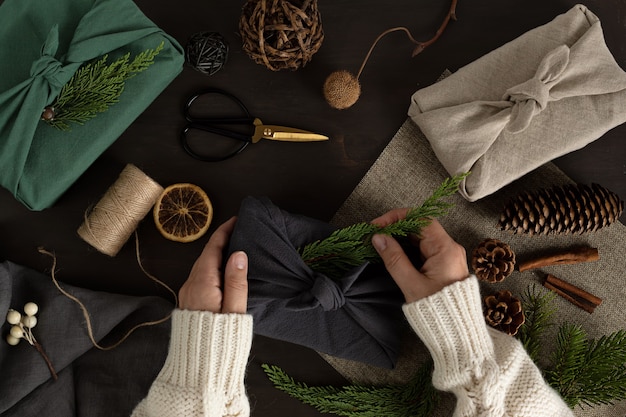 Woman hands wrapping Furoshiki gifts eco friendly alternative green Xmas presents