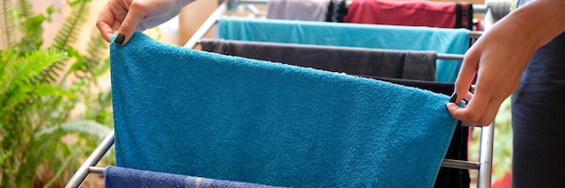 Woman hangs clean linen and towels on dryer at home closeup drying clothes concept