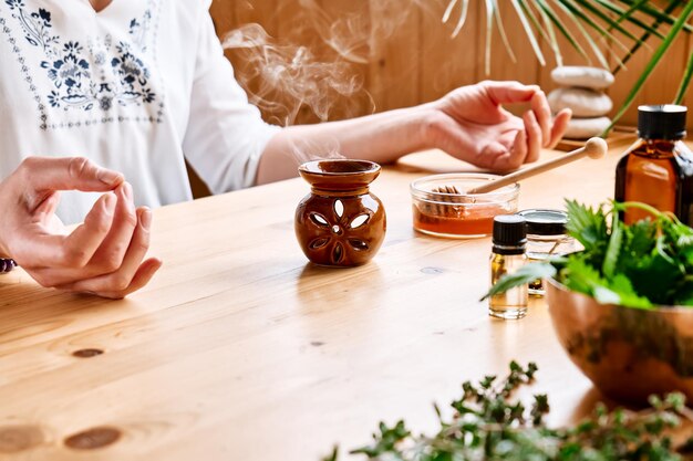 Photo woman has aromatherapy session at the table with essential oil diffuser  and medical herbs