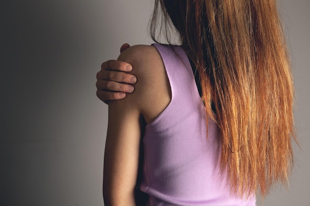 Woman has shoulder pain on gray background