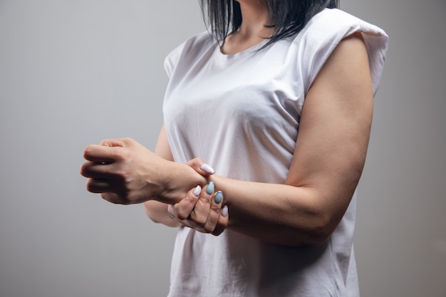 The woman has a sore wrist. joint pain on a gray wall