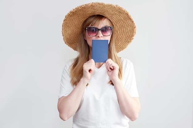 A woman in a hat and glasses with a passport on a white background