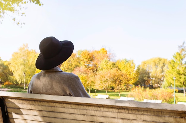 Woman in hat sitting in autumn park