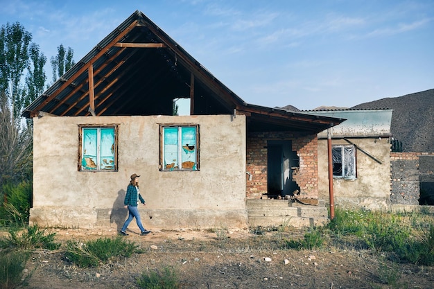 Woman in Hat walking near old house