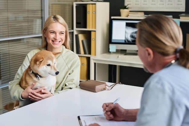 Woman Having Conversation with Veterinarian in His Office in Clinic