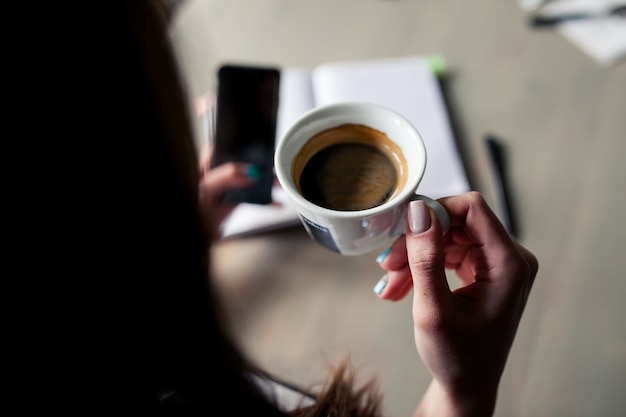 Woman having a cup of coffee while looking at her smartphone