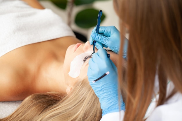 Woman having eyelash extension in professional beauty salon