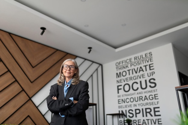 Woman head of a company in business clothes stands in the middle of a modern office