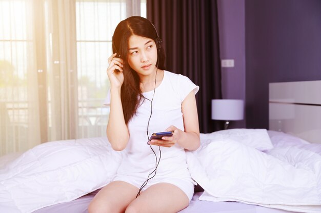 woman in headphones listening to music from smartphone