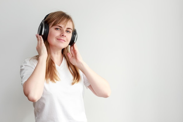 A woman in headphones listens to music on a white background