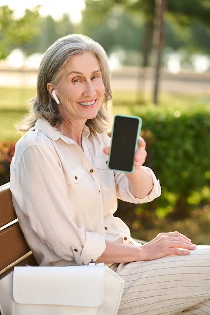 Woman in headphones showing smartphone screen