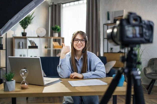 Woman in headset showing thumb up while filming video