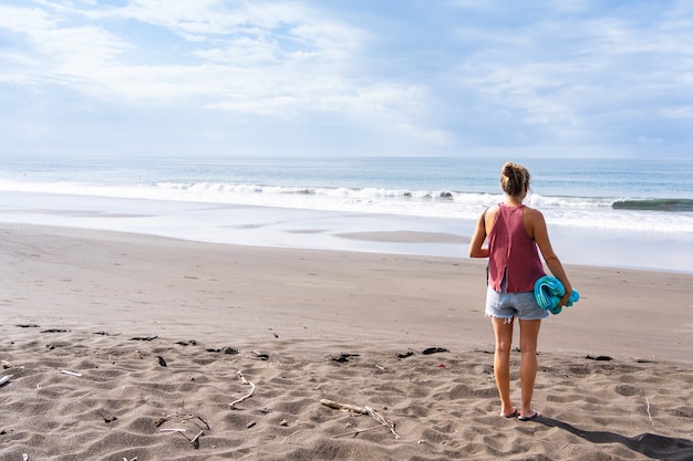 Woman on her back on a deserted beach looking at the sea