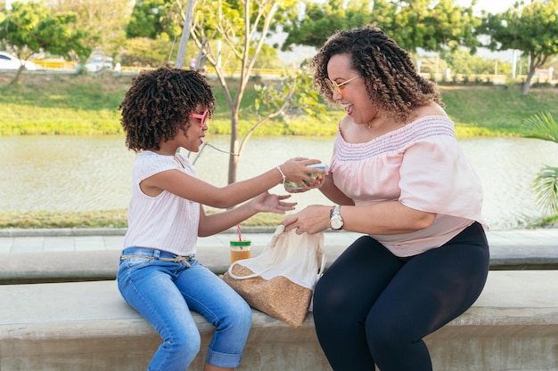 Woman and her daughter eating vegetables outdoors