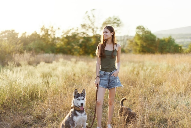 Woman and her husky dog happily walking and running in the grass in the field smile with teeth autumn sunset walk with a pet traveling with a friend dog happiness