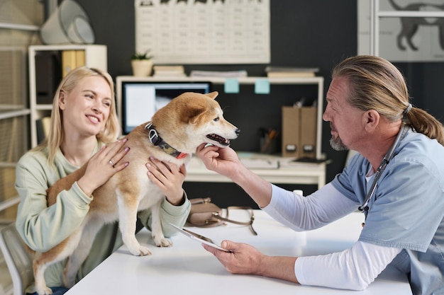 Photo woman and her shiba inu dog at appointment in veterinary clinic