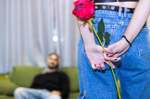 Woman hiding a gift on his back to deliver a surprise to his boyfriend on a special day at home Valentine39s Day birthday anniversary Christmas gift