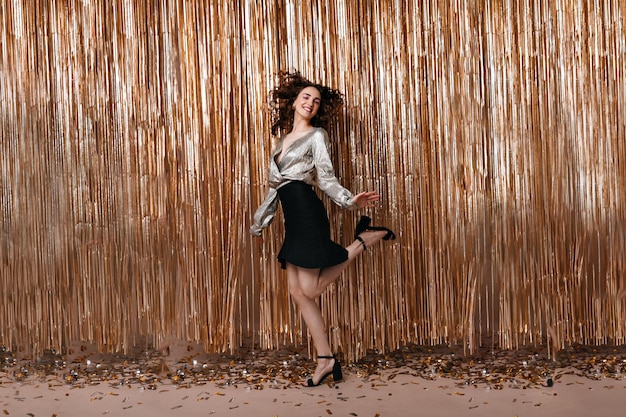 Woman in high spirit jumps on gold background