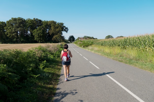 Woman hiker walking on the road