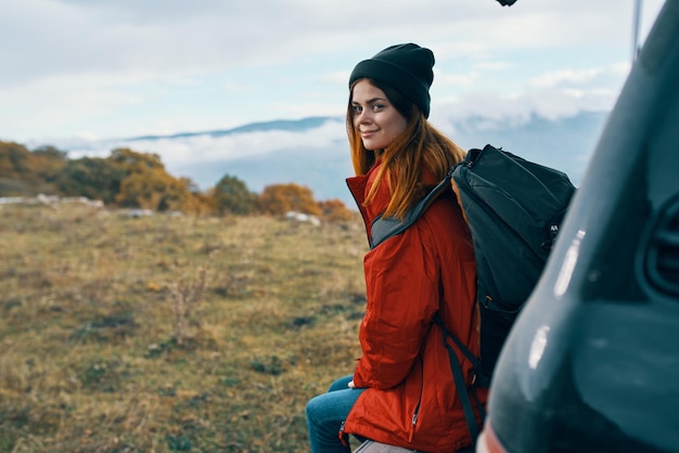 Woman hiker in warm clothes resting in the autumn in the mountains near the car