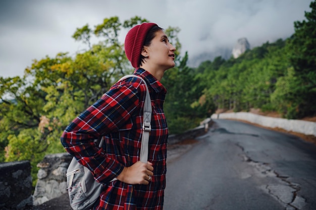 A woman hiker with a backpack enjoying a view of the mountains in the fog