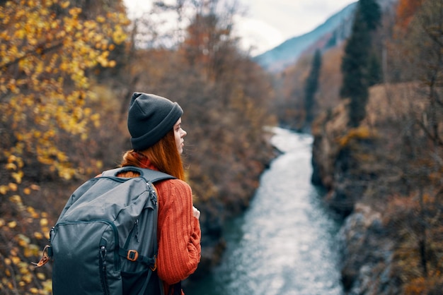 Woman hiker with backpack on her back near mountain river in nature