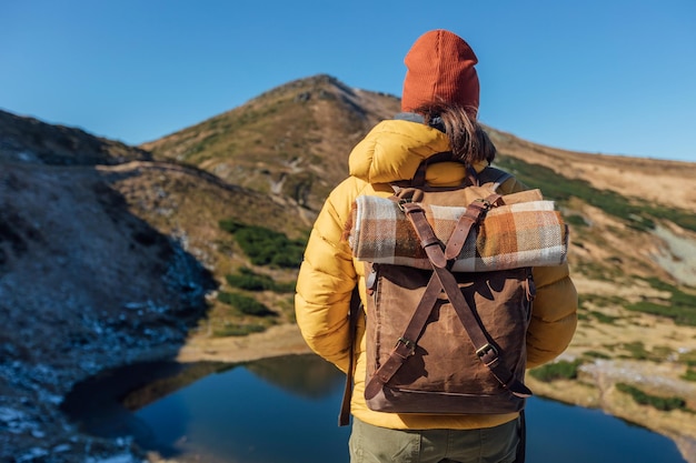 Woman hiker in yellow jacket with vintage backpack tourist girl with backpack hiking mountains at co