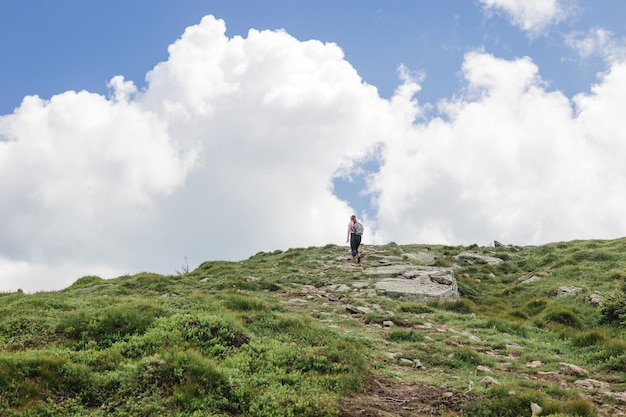 Woman hiking in mountains on a sunny summer day Freedom happiness travel and vacations concept outdoor activities Carpathian mountains Ukraine Europe Discover the beauty of earth