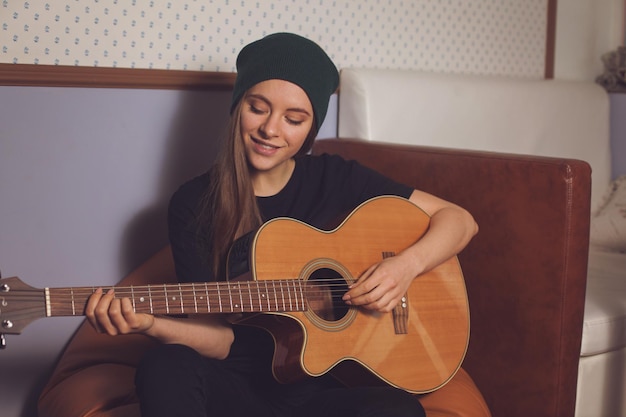 Woman hipster playing on guitar and enjoying music