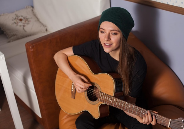 Woman hipster playing on guitar and singing