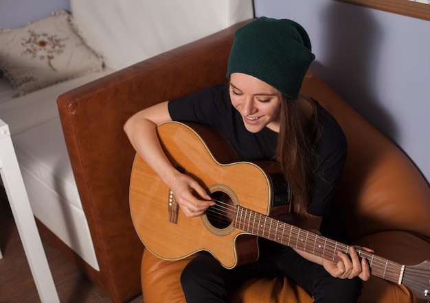 Woman hipster playing on guitar and singing