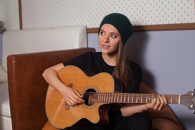 Woman hipster playing on guitar and singing