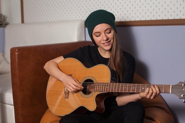 Woman hipster playing on guitar and singing