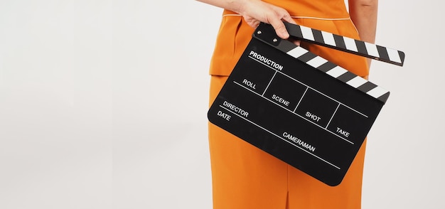 Woman hold clapper board and turn aroundShe wear a yellow suit on white backgroundBody part