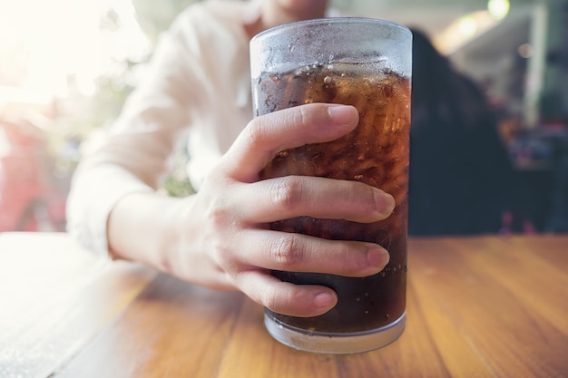 Woman hold a glass with soft drinks 