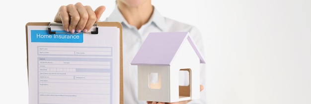 Woman hold home insurance document and house model closeup insurance agent property rental loan