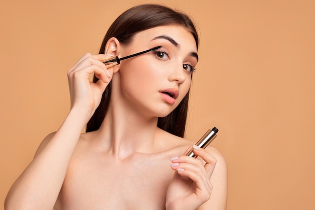 Woman hold mascara isolated on beige background