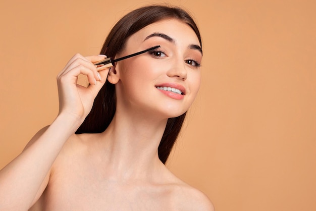 Woman hold mascara isolated on beige background