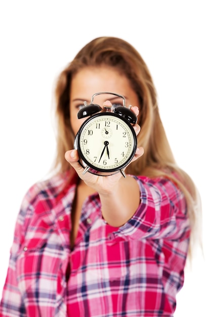 Photo woman holding alarm clock while standing against white background