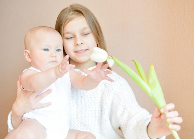 a woman holding a baby and the baby is holding a flower