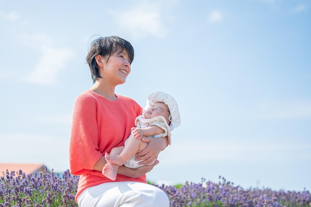 A woman holding a baby in a field of flowers