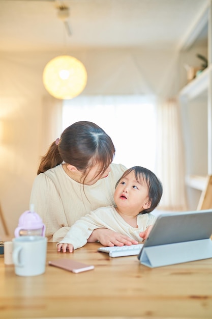 A woman holding a baby and operating a computer