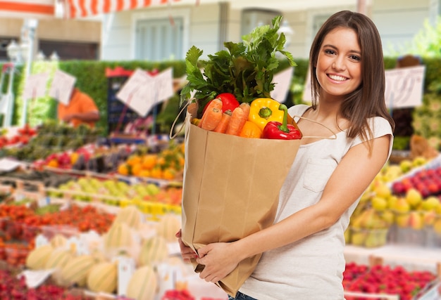 Woman holding a bag in a fruit and vegetable outdoor market